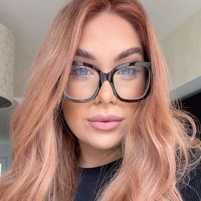 Portrait of Charlotte Golby with rose gold hair and black glasses at Golbylocks Salon Collective in Littlehampton